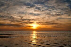 pôr do sol, iluminado mar. arenoso de praia dentro a primeiro plano. luz ondas. báltico mar foto