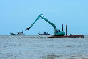 máquinas estão dragagem areia dentro a mar. foto