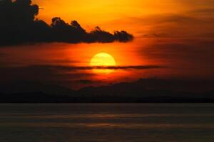 pôr do sol às a lago com Sombrio nuvem. foto
