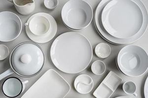 pilhas de pratos de cerâmica branca e vista superior de talheres em fundo cinza
