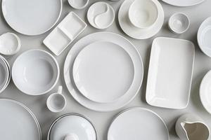 pilhas de pratos de cerâmica branca e vista superior de talheres em fundo cinza