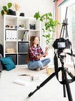 mulher fazendo um vídeo para seu blog sobre arte usando uma câmera digital montada em um tripé foto