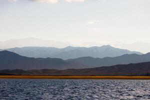 azul calma água dentro issyk-kul lago com montanhas em fundo às outono tarde foto