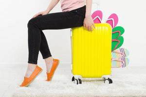 menina com mala isolada no fundo branco. férias de verão. chinelos ou chinelos de verão. mala de viagem ou bolsa. brincar. copie o espaço. modelo. em branco. foto