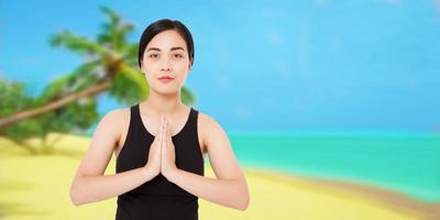 mulher bonita com mãos namaste, mulher coreana, meditação no mar da praia - conceito de verão foto