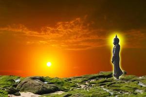 Buda olhando ao estilo de sete dias no céu do pôr do sol foto