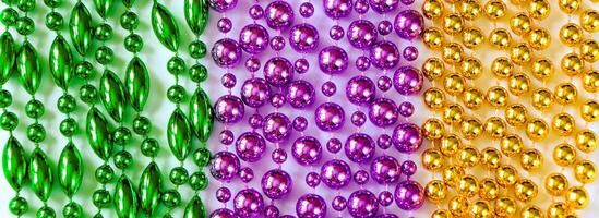 fundo de carnaval. close-up de miçangas multicoloridas. decorações festivas nas cores ouro, verde e roxo. símbolo de terça-feira gorda. foto