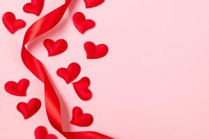 vermelho seda fita e corações em uma Rosa fundo. dia dos namorados dia, Lugar, colocar para texto. foto