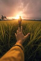 ai generativo pov Visão do uma feliz jovem mulher segurando mão do dela namorado enquanto caminhando de uma trigo campo às pôr do sol casal desfrutando viagem dentro a natureza foto