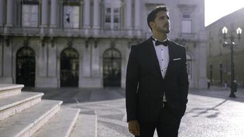 elegante homem dentro terno carrinhos em rua do europeu cidade. Ação. atraente homem dentro elegante terno em ensolarado verão dia. homem do sonhos Eu terno foto