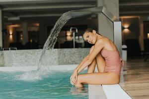 jovem mulher relaxante de a interior natação piscina foto