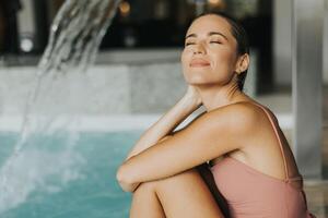 jovem mulher relaxante de a interior natação piscina foto