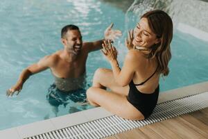 jovem casal tendo Diversão dentro a interior natação piscina foto