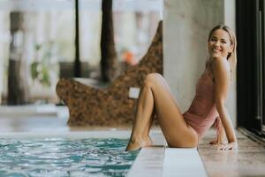 jovem mulher relaxante de a interior natação piscina foto
