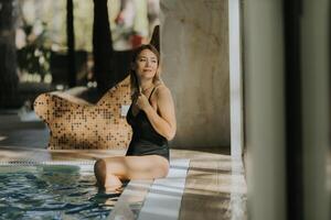 jovem mulher relaxante de a interior natação piscina foto