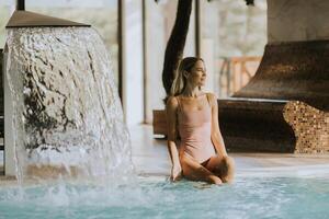 jovem mulher relaxante de a interior natação piscina foto