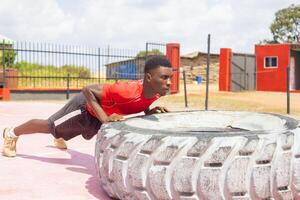 Forte desportivo cara lançando exercite-se roda às lado de fora Academia foto