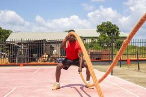 africano homem com batalha cordas exercício dentro a ginástica academia. foto
