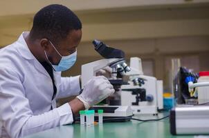 jovem bonito cientista ou médico dentro laboratório casaco trabalhando dentro biotecnológico laboratório, foto