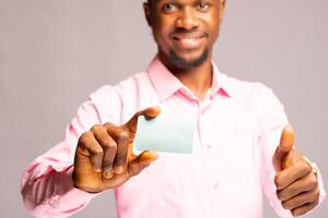 bonito africano homem sorridente Como ele detém é crédito cartão e fez polegares acima foto