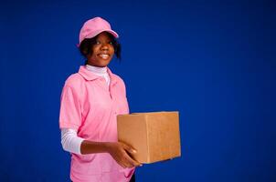 lindo jovem africano fêmea correio trabalhador segurando uma caixa foto