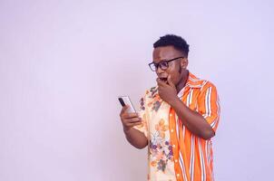 alegre africano americano homem dentro branco camisa usando Móvel telefone aplicativo. foto