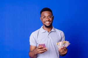 jovem africano homem de negocios segurando uma muitos do dinheiro e usando dele telefone foto