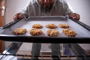 homem com biscoitos pronto para colocar dentro a forno. foto