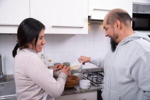 casal fala e tem Diversão enquanto preparando biscoitos às lar. foto