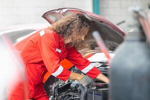 mecânico homem trabalhando dentro garagem armazém, jovem mecânico fixação carro dentro auto reparar fazer compras foto