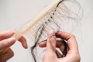 mulher asiática tem problema com perda de cabelo comprido anexar a escova de pente. foto