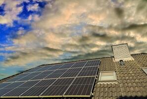 solar painéis produzindo limpar \ limpo energia em uma cobertura do uma residencial casa com uma pôr do sol céu. foto