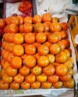 uma exibição do tomates e de outros frutas às uma mercado foto