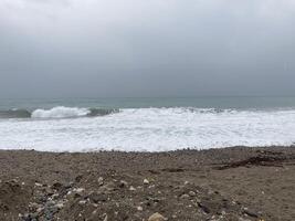 a turbulento mar tempestades a costa do areia misturado com pedrinhas foto