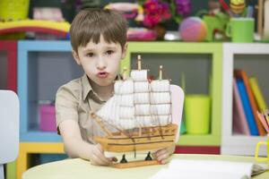 Garoto jogando com navio.criança com uma brinquedo barco a vela foto