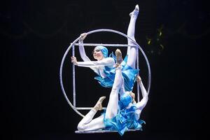 dois acrobata meninas mostrar uma circo número em uma Sombrio fundo. acrobático desempenho. foto