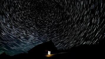 de madeira casa dentro a montanhas dentro inverno. Estrela trilhas dentro a noite céu. foto