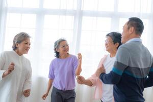 ásia Mais velho masculino e fêmeas pessoas dança com seus parceiros em uma dançando chão dentro vivo espaço. feliz Mais velho casal realizando pegue exercício. alegre despreocupado aposentado Senior amigos desfrutando relaxamento foto