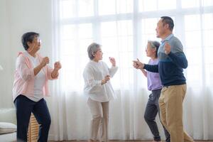 ásia Mais velho masculino e fêmeas pessoas dança com seus parceiros em uma dançando chão dentro vivo espaço. feliz Mais velho casal realizando pegue exercício. alegre despreocupado aposentado Senior amigos desfrutando relaxamento foto