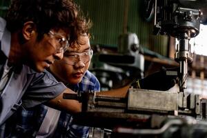 ásia trabalhador dentro Produção plantar perfuração às máquina. profissional trabalhador perto perfuração máquina em fábrica. acabamento metal trabalhando interno aço superfície em torno moedor máquina com vôo faíscas. foto