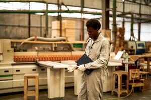 africano homem trabalhadores Engenharia em pé com confiança com trabalhando suíte vestir e mão luva dentro frente máquina. conceito do inteligente indústria trabalhador operativo. madeira fábrica produzir madeira palato. foto