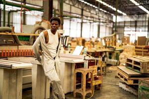 africano homem trabalhadores Engenharia em pé com confiança com trabalhando suíte vestir e mão luva dentro frente máquina. conceito do inteligente indústria trabalhador operativo. madeira fábrica produzir madeira palato. foto