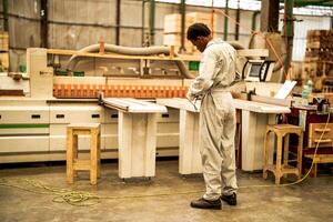 africano homem trabalhadores Engenharia em pé com confiança com trabalhando suíte vestir e mão luva dentro frente máquina. conceito do inteligente indústria trabalhador operativo. madeira fábrica produzir madeira palato. foto