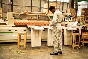 africano homem trabalhadores Engenharia em pé com confiança com trabalhando suíte vestir e mão luva dentro frente máquina. conceito do inteligente indústria trabalhador operativo. madeira fábrica produzir madeira palato. foto