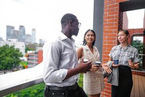 equipe do o negócio pessoas inteligente homem e mulheres ficar de pé às ao ar livre terraço construção e conversa juntos com café da manhã Comida e café em a mão dentro Boa sentindo-me com cidade espaço prédio. o negócio manhã. foto