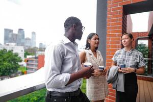 equipe do o negócio pessoas inteligente homem e mulheres ficar de pé às ao ar livre terraço construção e conversa juntos com café da manhã Comida e café em a mão dentro Boa sentindo-me com cidade espaço prédio. o negócio manhã. foto