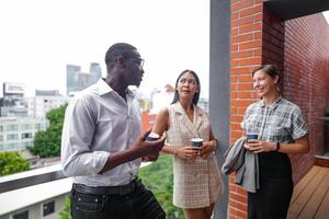 equipe do o negócio pessoas inteligente homem e mulheres ficar de pé às ao ar livre terraço construção e conversa juntos com café da manhã Comida e café em a mão dentro Boa sentindo-me com cidade espaço prédio. o negócio manhã. foto