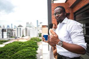 africano o negócio inteligente homem carrinhos às ao ar livre terraço prédio. pessoas com em mão dentro Boa sentindo-me com cidade espaço prédio. relaxante do pessoas o negócio manhã. foto