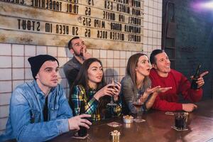 grupo do jovem lindo amigos assistindo televisão e torcendo para º foto