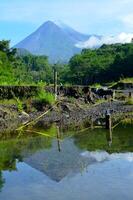 merapi vulcão com Está reflexão a partir de pequeno poça foto